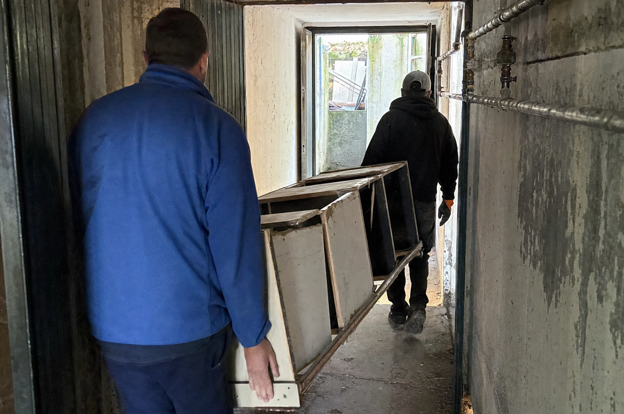 Zwei Helfer tragen sperrige Möbel aus dem Haus ins Freie